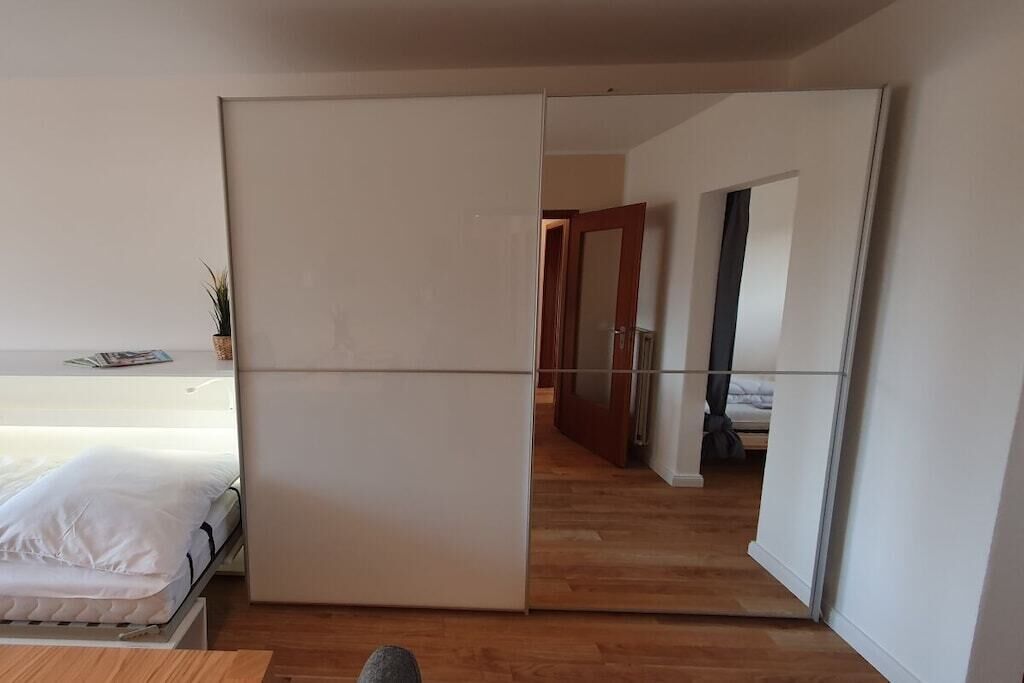 Huone, jossa on sänky, valkoinen vaatekaappi ja puulattia.