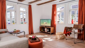 Ein Wohnzimmer mit einer Couch, einem Couchtisch, einem Fernseher und einem Bücherregal.