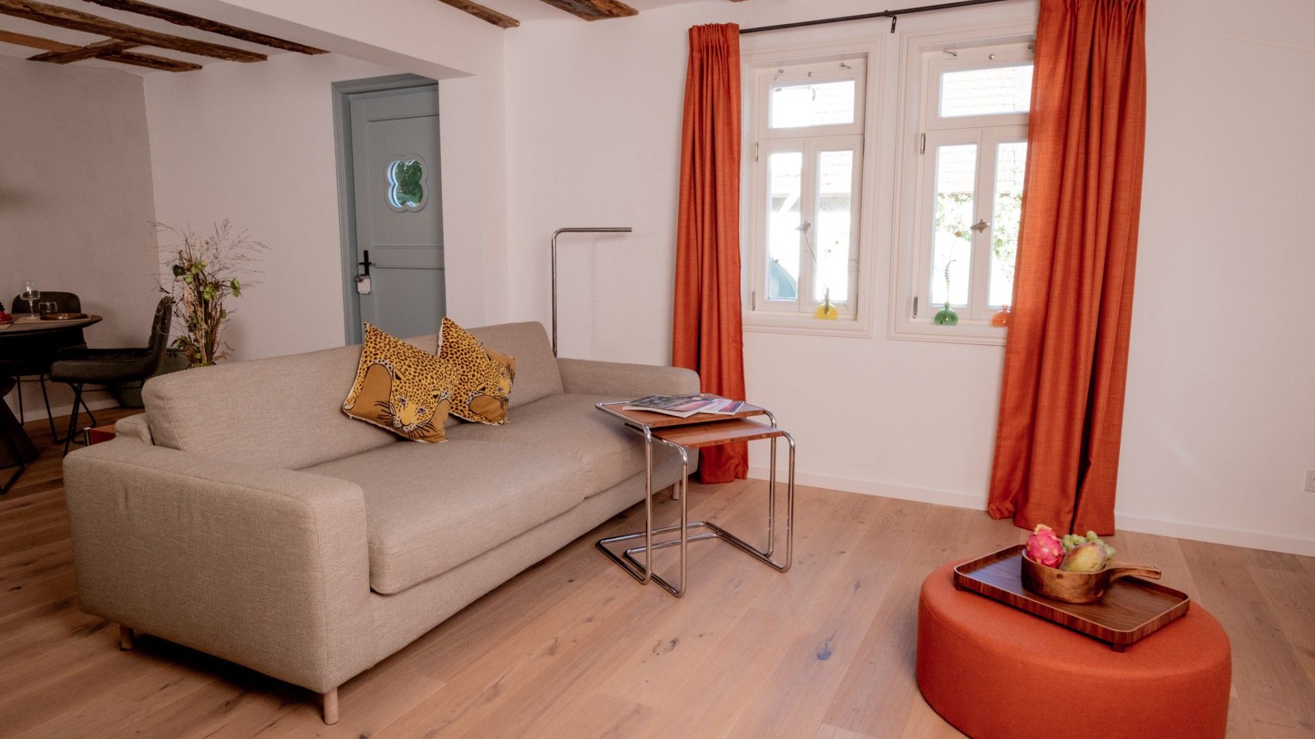 A living room with a sofa, a side table, a floor lamp, and a window with curtains.