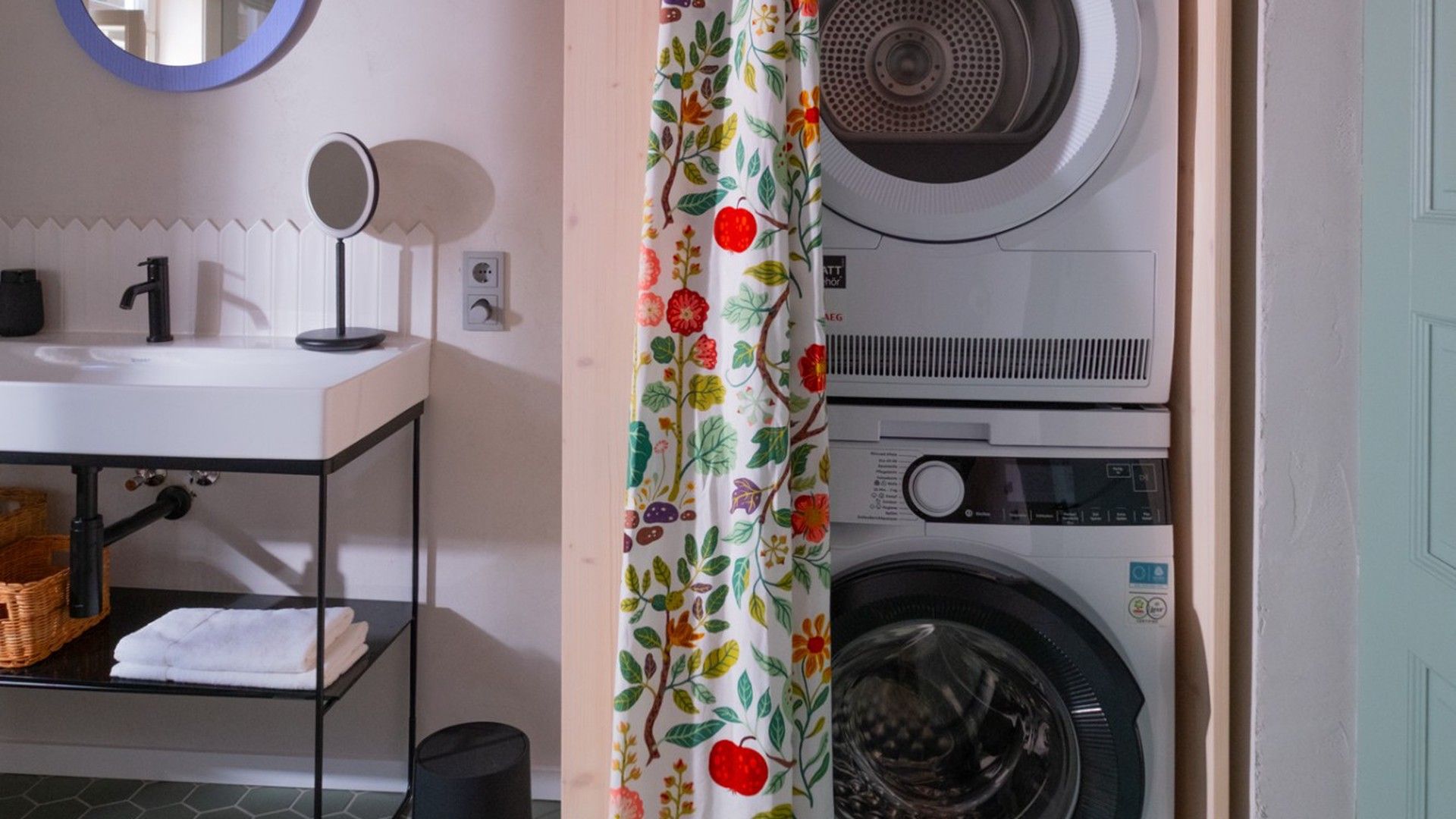 A laundry area with a washing machine, dryer, and a sink with a mirror.