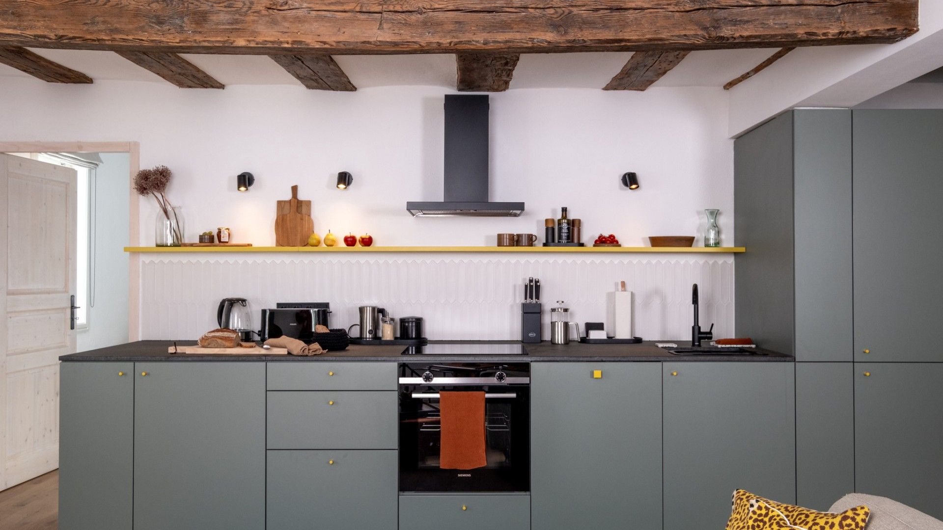 A modern kitchen with grey cabinets, a built-in oven, and a wooden ceiling.