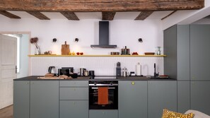 Een moderne keuken met grijze kastjes, een inbouwoven en een houten plafond.