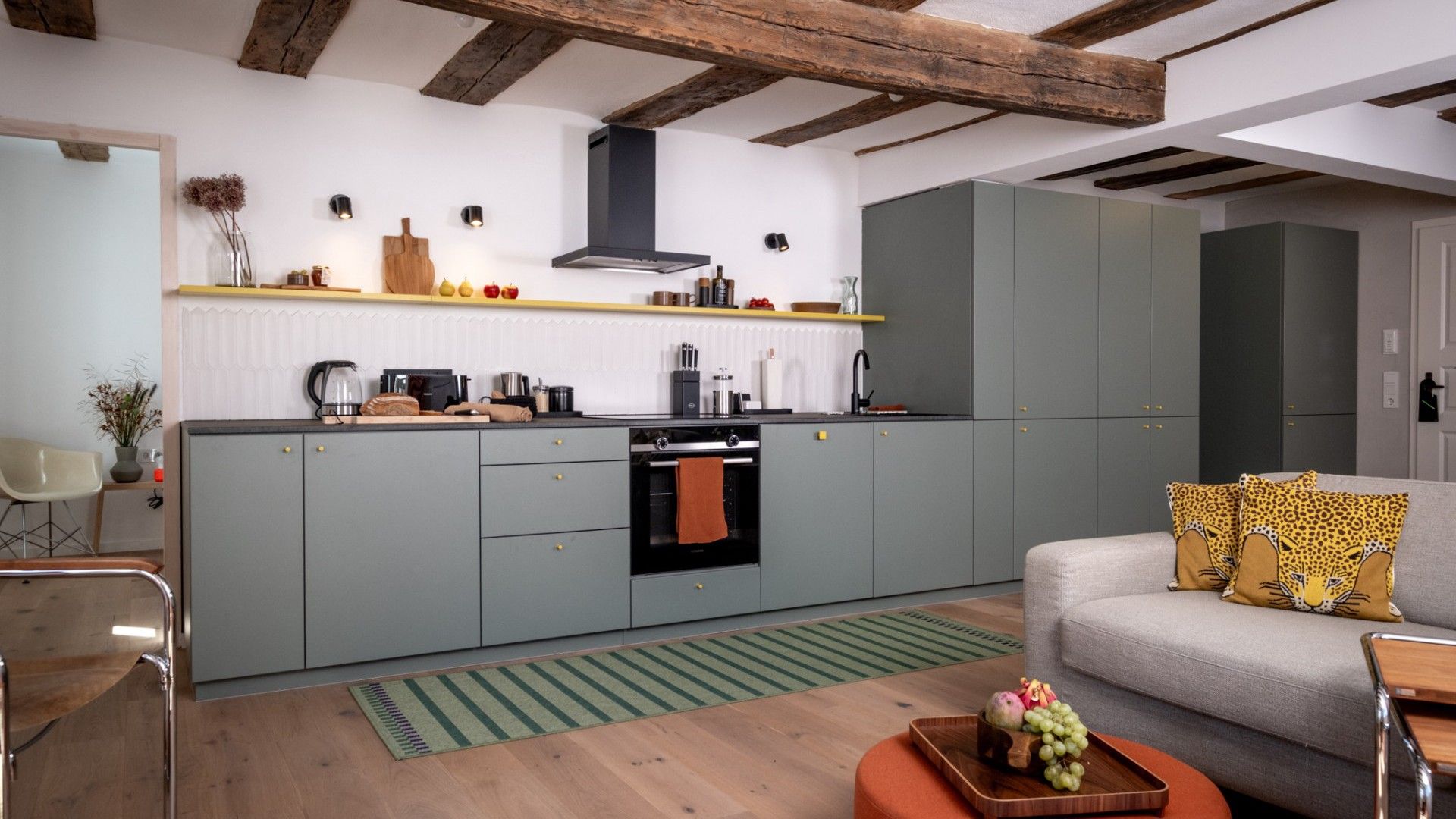 A modern kitchen with grey cabinets, a built-in oven, and a wooden ceiling.