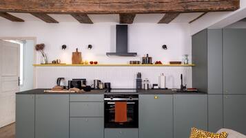 A modern kitchen with grey cabinets, a built-in oven, and a wooden ceiling.