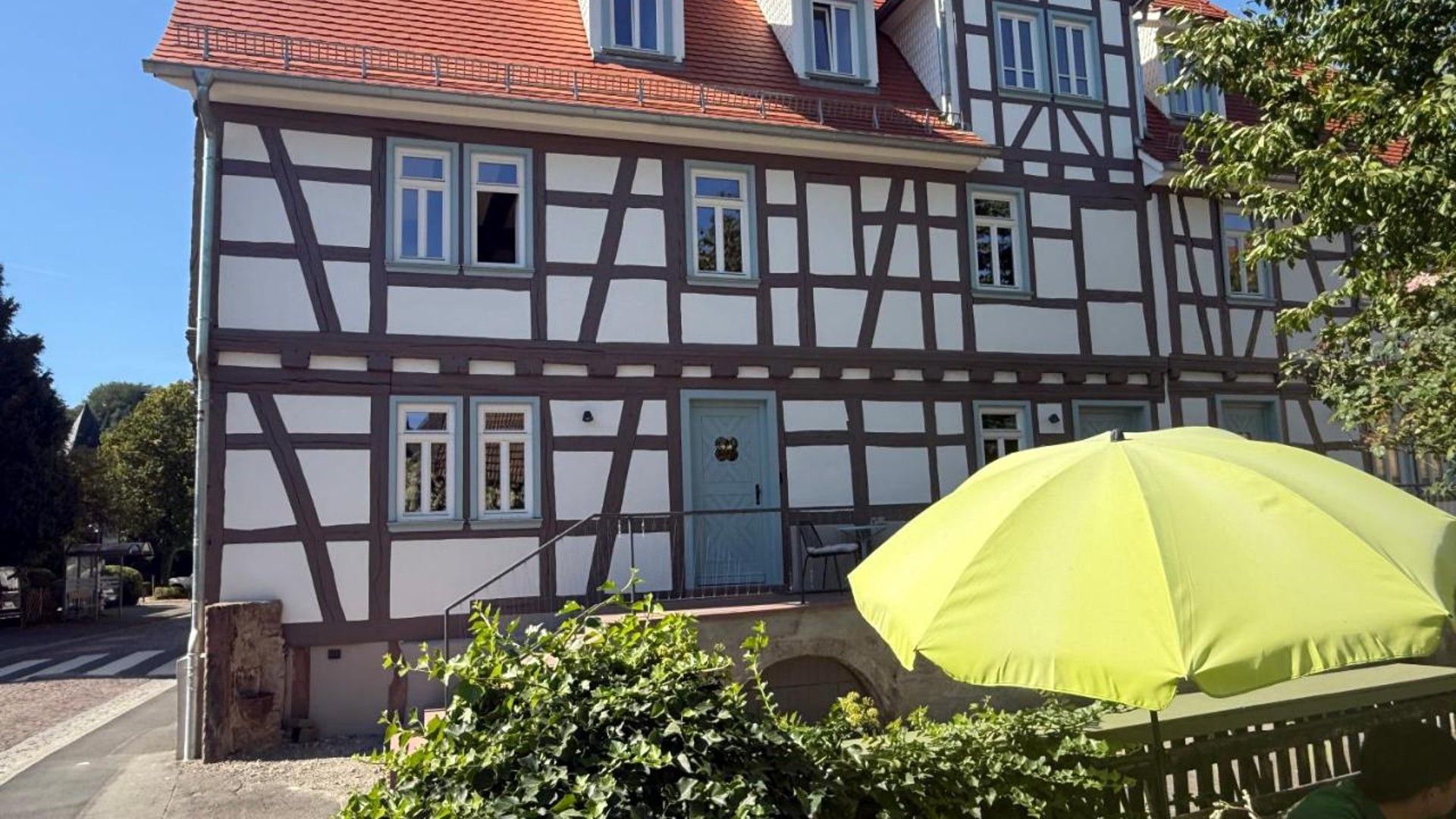 Ein traditionelles Fachwerkhäuschen mit blauer Tür und zahlreichen Fenstern.