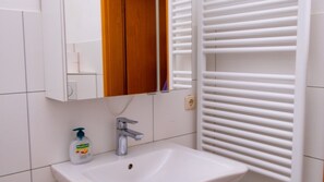 Un baño con un lavamanos blanco, un espejo y un mueble de madera.