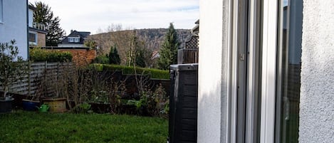 Ein Wohnhaus mit gepflegtem Rasen, Holzzaun und Blick auf eine Hügelkette.