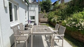 Un patio al aire libre con una mesa y sillas, un banco y una mesita con una silla.