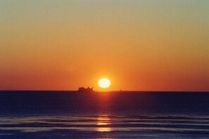 A sunset over the ocean with a ship in the distance. - Wadden Sea pearl Bredland (Nieblum)
