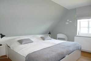 A bedroom with a bed, bedside tables, a chair, and a window. - Wadden Sea pearl Bredland (Nieblum)