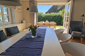 Un espace repas avec une longue table, des chaises et une vue sur le jardin.
