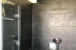 Ein Duschbereich mit Glasabtrennung und Handbrause.