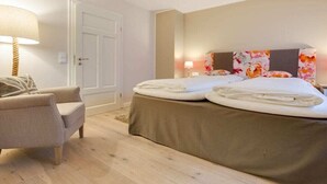 Quarto com cama, cadeira, porta e parede com interruptor de luz.