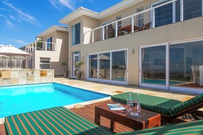 A modern two-story house with a swimming pool, outdoor furniture, and large sliding glass doors. - Stunning house on Pezula Championship Course, 4 bedrooms ensuite, private pool (Knysna)