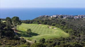 Un campo de golf con vistas al mar, rodeado de edificios residenciales.
