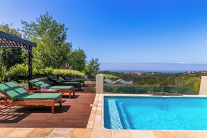Un área de piscina con sillas de descanso y vista al océano.