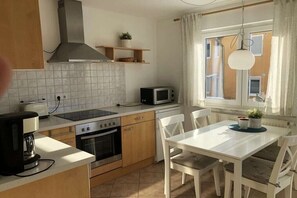 Eine Küche mit Herd, Backofen, Mikrowelle und einem Esstisch mit Stühlen.