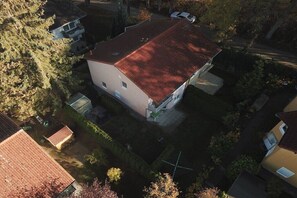 Vista aérea de un barrio residencial con una casa de techo rojo, un pequeño jardín y viviendas vecinas.