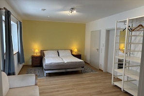 Ein Schlafzimmer mit einem Bett, Nachttischen, einem Kleiderschrank und einer Kleiderstange.
