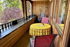 Eine Holzhütte mit einem runden Tisch und einem Stuhl, ein Fenster mit Blick auf Bäume und ein Regal mit Dekoration.