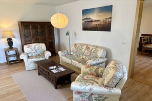 Ein Wohnzimmer mit einer Sofagarnitur, einem Couchtisch, einer Lampe und einem Gemälde an der Wand.