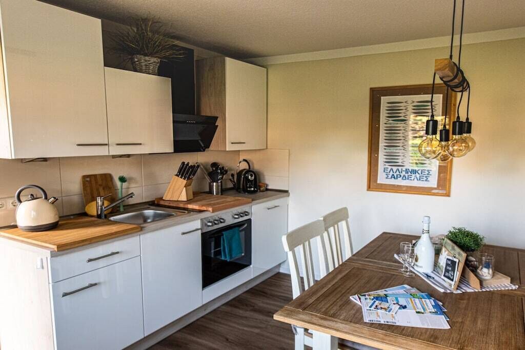 Een moderne keuken met witte kasten, een houten aanrecht en een eettafel met een placemat.