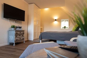 Une chambre à coucher avec un lit, une commode, un téléviseur et une fenêtre.