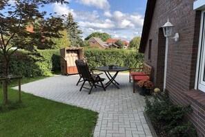 A patio with a table and chairs, a wooden bench, and a potted plant. - Holiday apartment with 1 bedroom (Dornum)