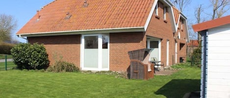 A brick house with a sloped roof, a front door, and a small porch area.