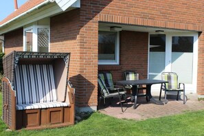 A patio with a brick house, a wooden bench, and a table with chairs. - Holiday home in Fehmarn with swimming pool (Fehmarn)