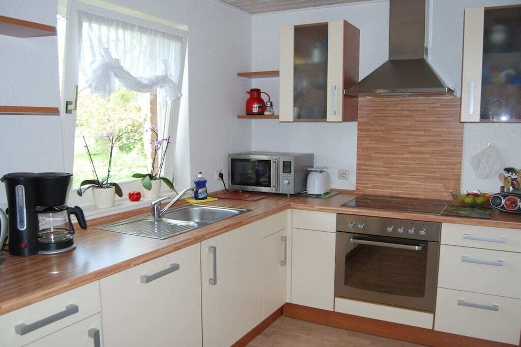 A modern kitchen with white cabinets, a stainless steel oven, a microwave, and a coffee maker.
