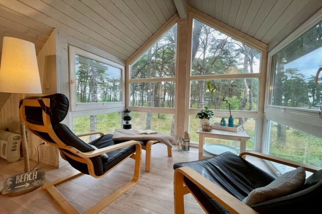 A cozy room with a large window, a chair, a small table, and a lamp.