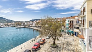 A coastal town with a marina, parked cars, and buildings along the waterfront.
