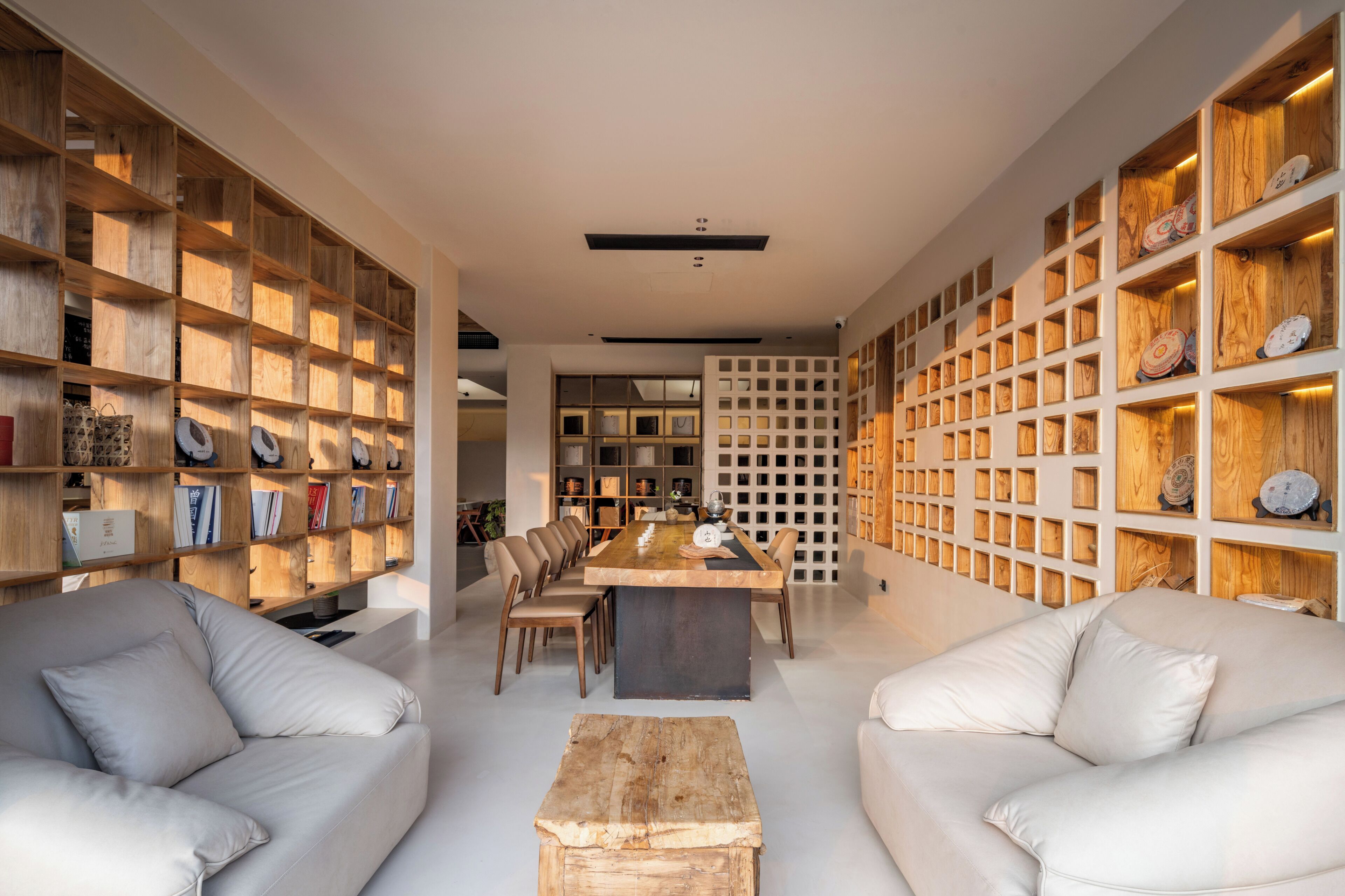 A modern interior with a dining area, sofas, and wooden shelving units.