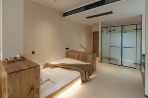 A modern bedroom with a wooden bed, bedside table, and a glass-enclosed walk-in closet.
