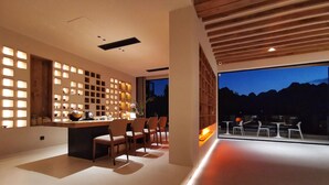 Un interior moderno con comedor, cocina con barra y un amplio ventanal con vistas a un paisaje montañoso.