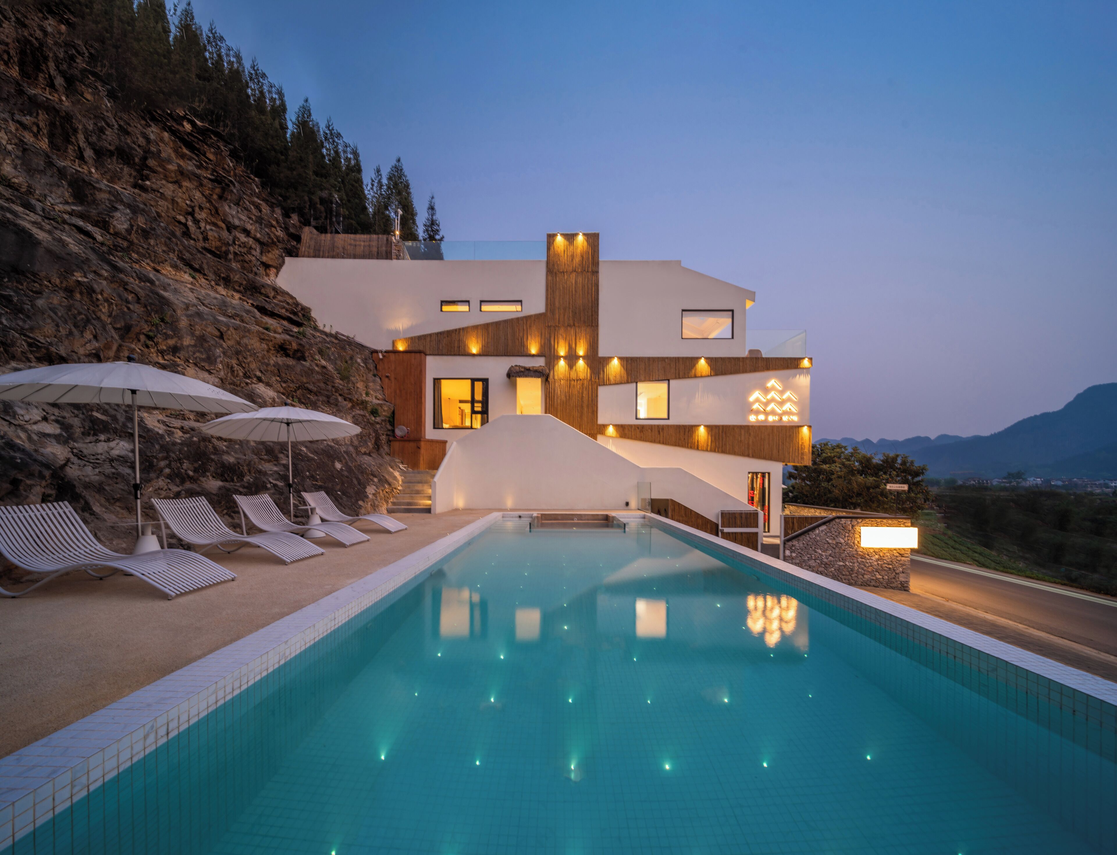 Ein modernes Haus mit Swimmingpool, Sitzgelegenheiten im Freien und Bergblick.