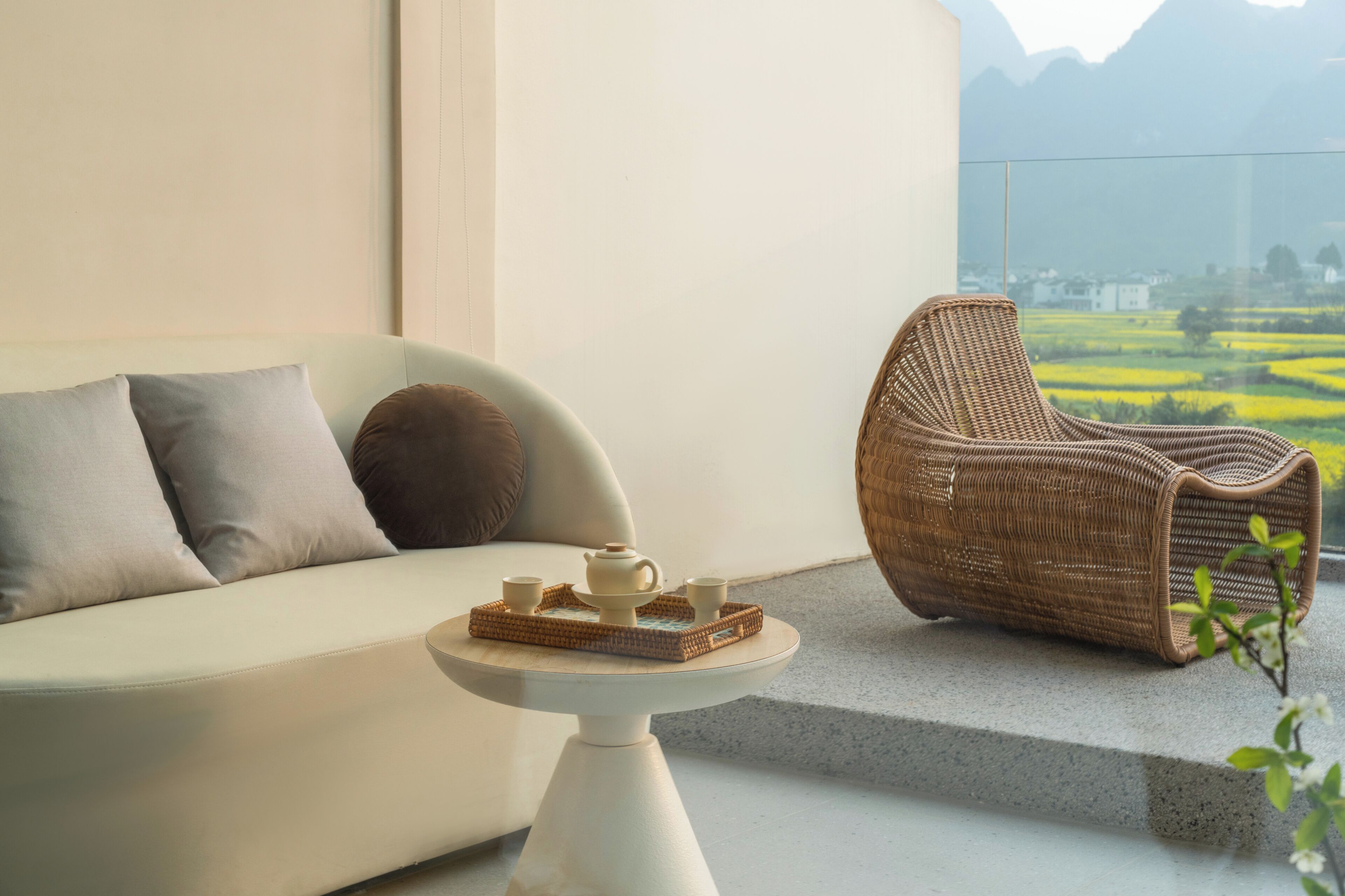 A modern living space with a sofa, a wicker chair, and a small table with a tray of tea set.