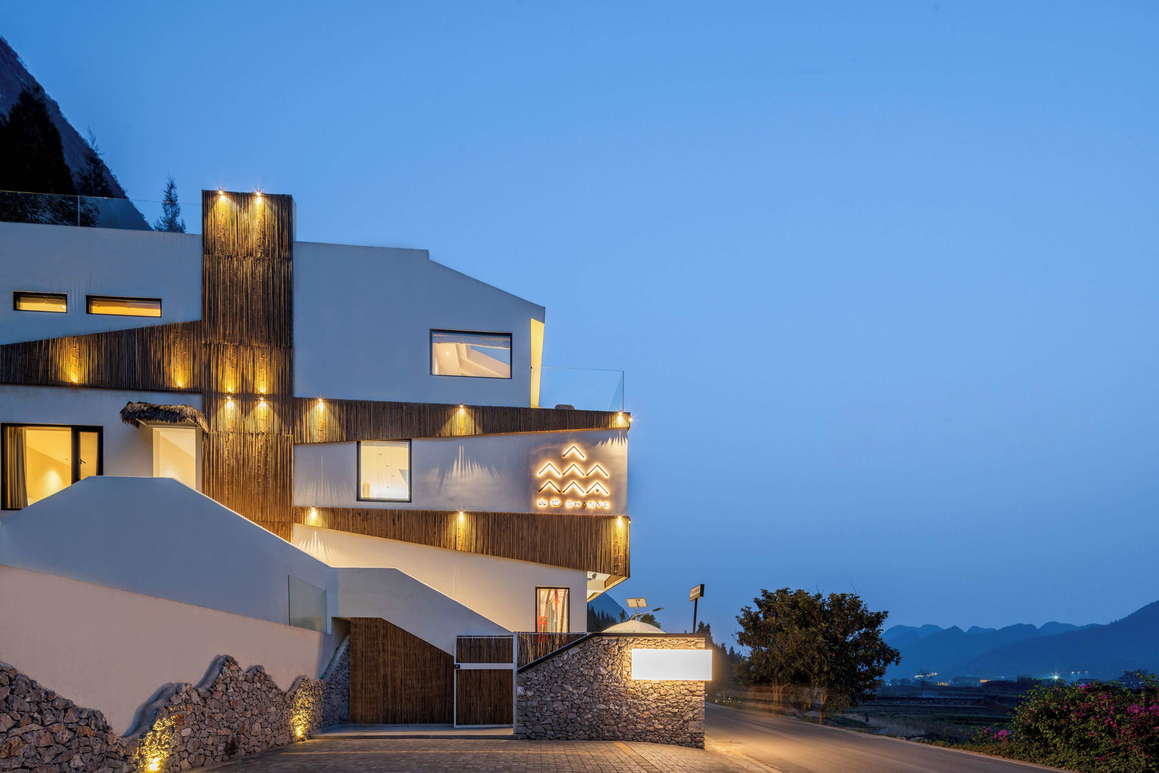 A modern multi-story building with a unique architectural design, featuring a combination of wooden and stone elements.