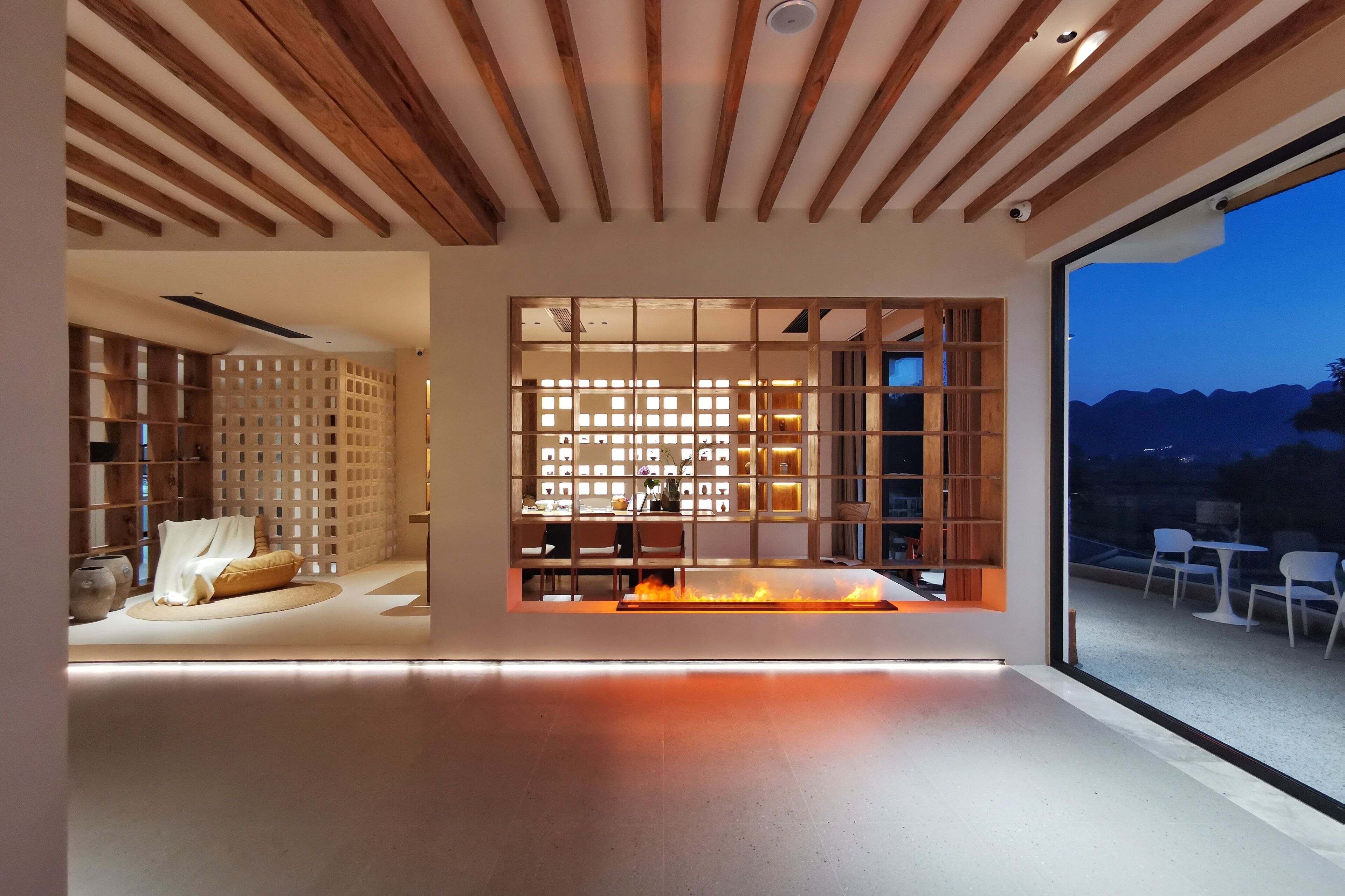 Un intérieur moderne avec un plafond en bois, une cheminée et une vue sur l’extérieur.