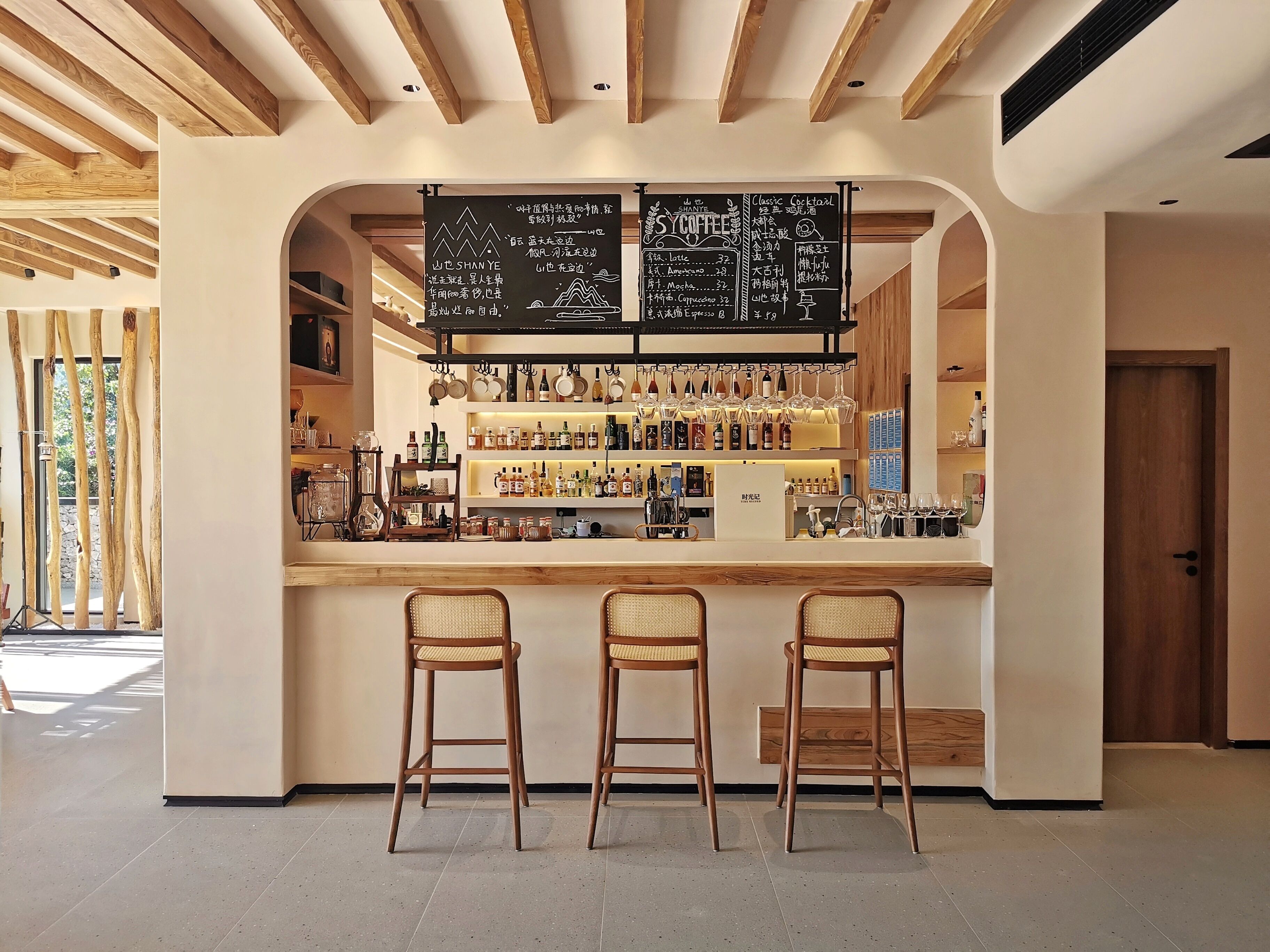 A bar area with a wooden ceiling, a chalkboard menu, and bar stools.