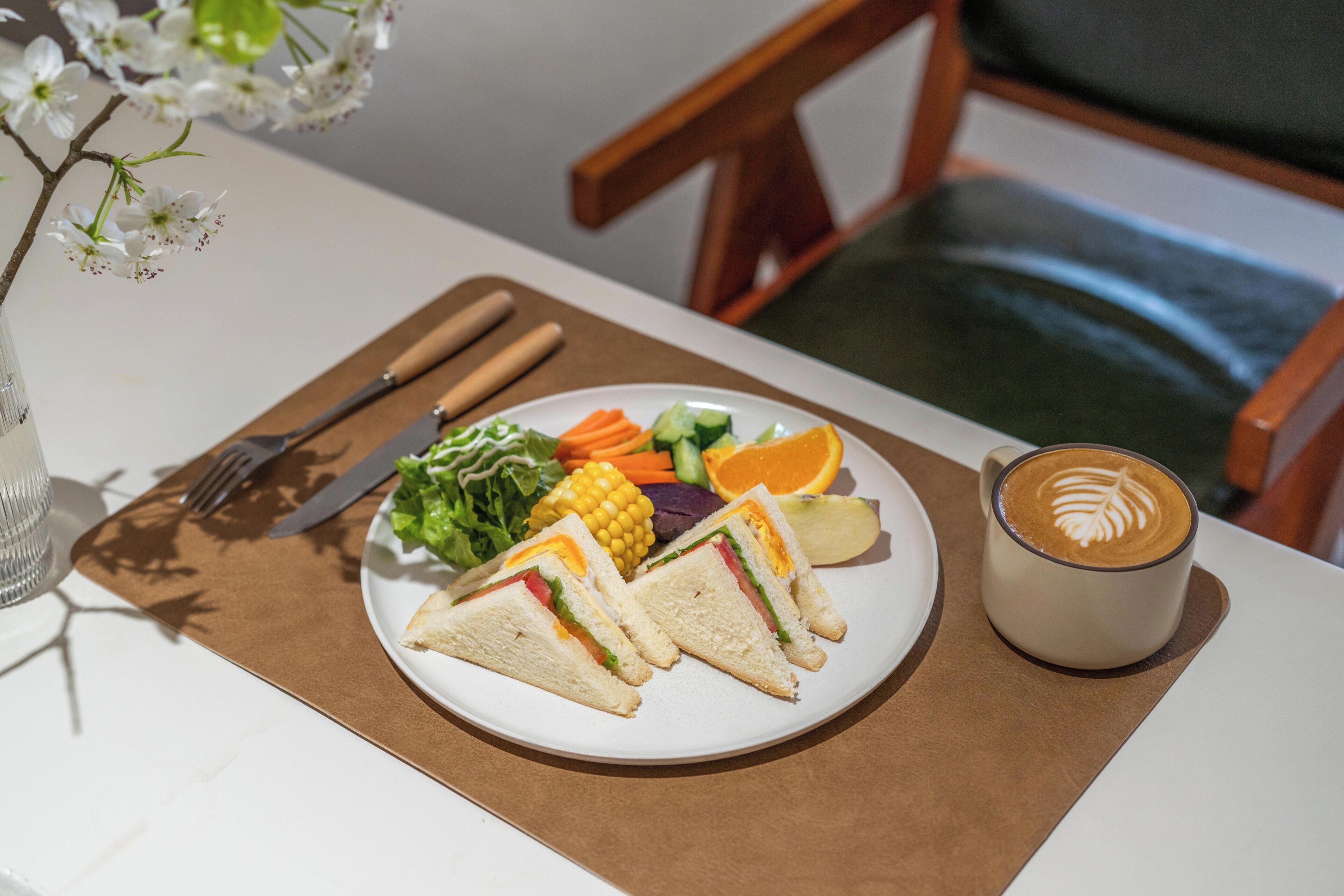 A plate with sandwiches, vegetables, and a cup of coffee on a table.