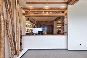A reception area with a wooden counter, a computer monitor, and shelves with various items.