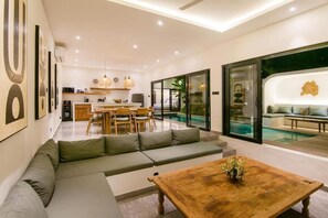 Ein modernes Wohnzimmer mit Sofa, Couchtisch und Essbereich.