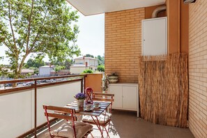 A balcony with a table, chairs, and a potted plant.