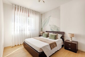 Una camera da letto con un letto, comodini, una lampada e una parete decorata con un motivo a foglia.