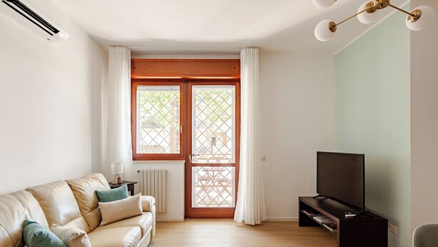 Una sala de estar con un sofá, un televisor y una ventana con cortinas.