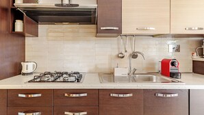 Una cocina moderna con estufa a gas, pileta de acero inoxidable y muebles de madera.