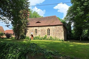 Ein Gebäude aus Stein mit einem geneigten Dach, gewölbten Fenstern und einer kleinen Tür.