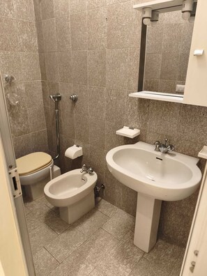 Une salle de bain équipée de toilettes, d’un bidet et d’un lavabo.